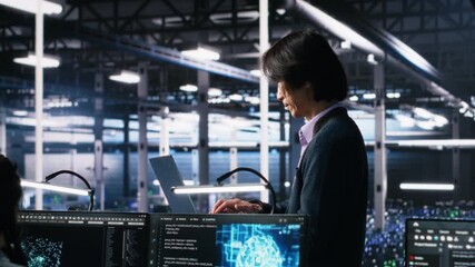 Team leader supervising technicians in server room using AI to review infrastructure diagnostics. Asian man in data center analyzing performance of workers using artificial intelligence, camera A - Powered by Adobe