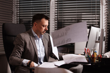 Stressed office worker typing on laptop as papers fly around him. Overwhelmed business atmosphere,...