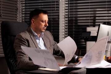 Stressed office worker typing on laptop as papers fly around him. Overwhelmed business atmosphere,...