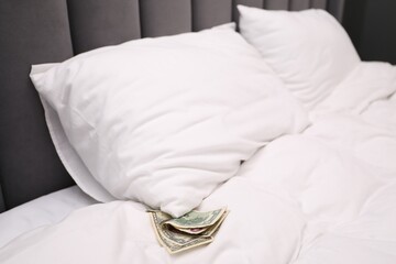 Tips under pillow on bed in hotel, closeup. Gratuity for work