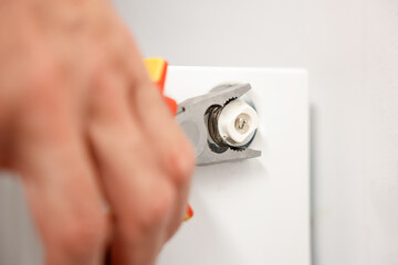 Man fixing heating radiator with pliers indoors, closeup