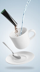 Instant coffee making. Combining granules from sachet and water in cup against light background
