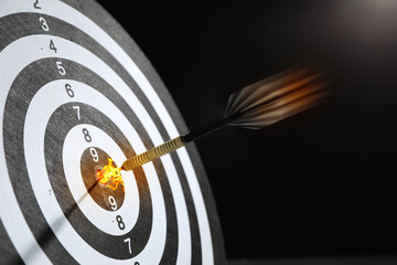 Dart with flames hit center of target against black background, motion blur effect