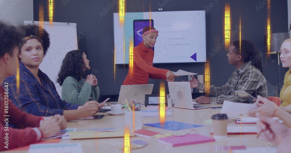 Poster presenter in red turtleneck and headband handing document in meeting room with laptops and screen