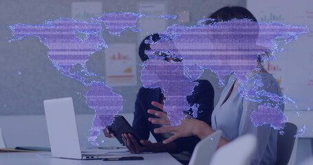 Analyzing business colleagues reviewing data at meeting table, with laptop, holographic map overlay