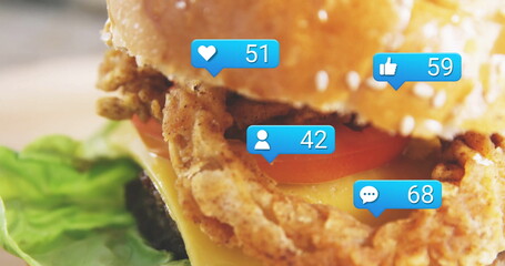 Showing chicken sandwich with sesame bun, cheese, tomato in kitchen, blue notification icons