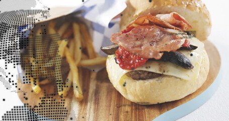 Displaying sesame burger with beef patty, cheese, peppers, mushrooms on board with paper cone fries