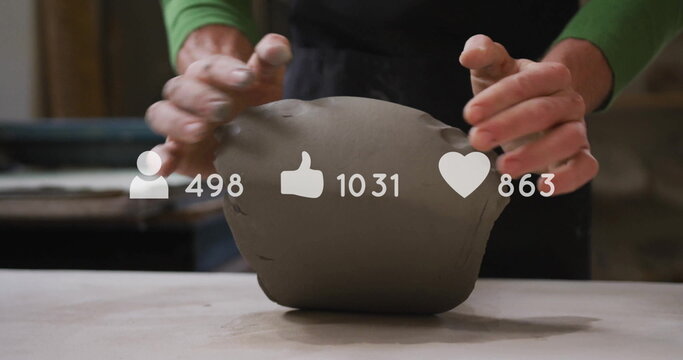Shaping apron-clad hands molding clay on tabletop in ceramics studio, social media icons overlay - Powered by Adobe