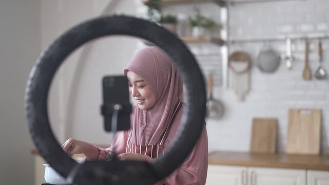 Muslim woman vlogger live streaming cooking online in kitchen look at camera with vegetables, content creator culinary class at home studio, halal food influencer cooking live, video for social media