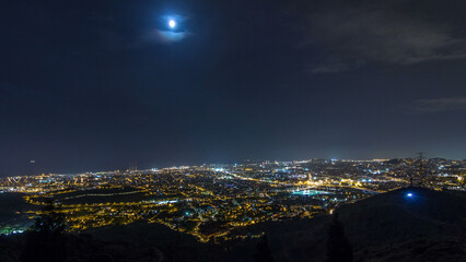 Barcelona and Badalona skyline with roofs of houses and sea on the horizon night timelapse