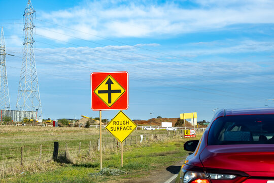 Road warning signs indicating an upcoming intersection and rough surface, at Tarneit, an outer suburb of Melbourne, Australia.