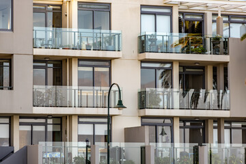 Contemporary apartment facade with glass balconies in a coastal urban environment. Modern stylish and upscale residential architecture.