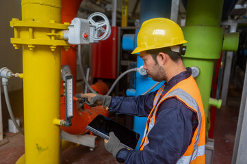 A male engineer is checking the pressure system of a gas pipeline in an industrial plant