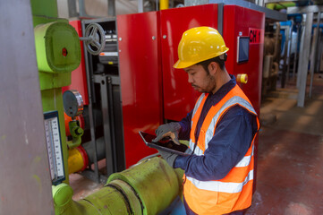 A male engineer is checking the pressure system of a gas pipeline in an industrial plant