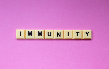 IMMUNITY  word with alphabet cubes isolated on pink background
