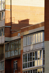 Close view of a multi-story apartment building with enclosed glass balconies, brick walls, and warm...