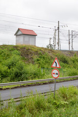 Rural road with curve and no overtaking signs near railway infrastructure, green vegetation, small...