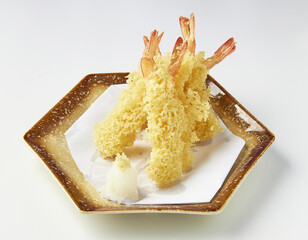 Crispy golden tempura shrimp served on decorative plate with side of grated daikon radish,...