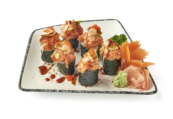 Spicy tuna sushi rolls garnished with fish roe, avocado, and spicy mayo, served on ceramic plate with pickled ginger, wasabi, and carrot garnish