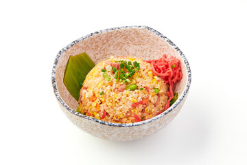 Bowl of vibrant egg fried rice garnished with chopped green onions and pickled ginger, served in decorative ceramic bowl with banana leaf for presentation