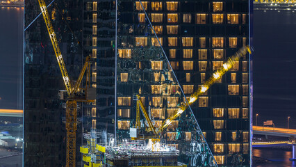 Construction site with crane at JBR night timelapse. Building of skyscrapers.