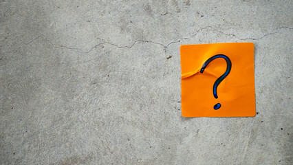 Blue Question Mark on an Orange Sticky Note on a Cracked Concrete Background