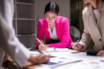 A woman in a pink jacket is writing in a notebook