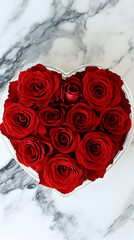 Red roses arranged in a heart-shaped white box on a marble surface.