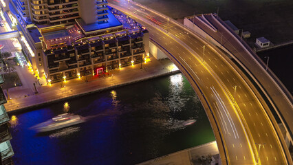Dubai Marina at night aerial view to canal with boats and bridge with traffic timelapse near hotel