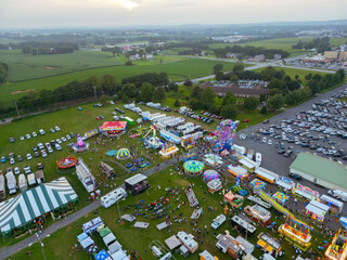 Aerial drone view of a county fair, dirt track, and a parking lot with cars. Amusement rides. Children. Fun. 