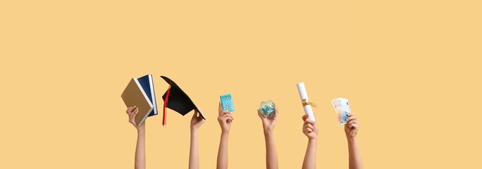 Female hands holding piggy bank, graduation hat, diploma, calculator, books and money on yellow...