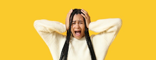 Stressed African-American woman screaming on yellow background