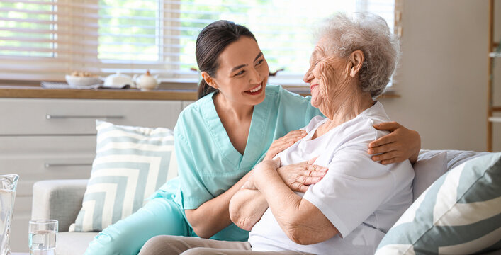 Physical therapist hugging senior woman on sofa at home
