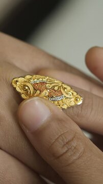 Closeup of fingers wearing 18k HUID certified handcrafted gold finger ring, Vertical