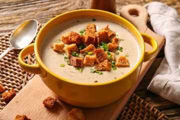 Pot of tasty cream soup with croutons on table