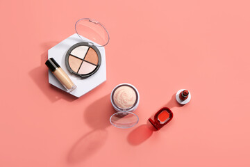Stand with different decorative cosmetics on pink background