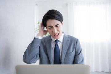 パソコンの前で頭を抱える　もう仕事のストレスすごすぎる…