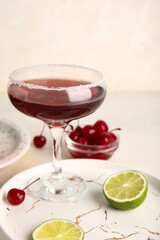 Glass of Cosmopolitan cocktail with cherries and lime on white background