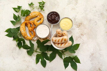Bowl with tasty Bavarian sausages, sauces, pretzels and mug of beer on beige background....