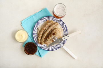 Plate with tasty Bavarian sausages, sauces, sauerkraut and glass of beer on white background....