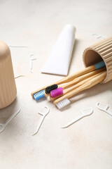 Cup with toothbrushes, tube of toothpaste and floss toothpicks on beige grunge background