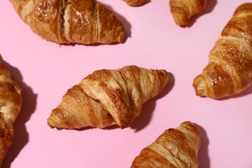 Many tasty croissants on pink background