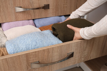 Woman taking sweater from chest of drawers at home