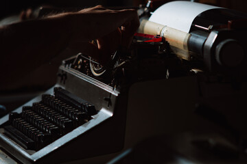 Close-up of hands typing on an old noir vintage typewriter in dramatic low light