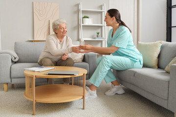 Senior woman taking bottle of water from physical therapist at home