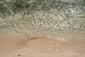 ガラスのように透明な波が打ち寄せる穏やかな波打ち際