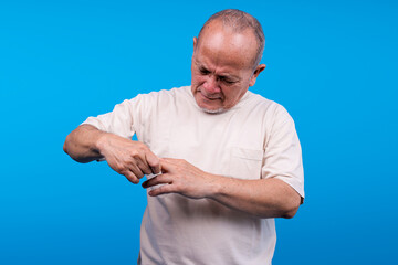 Elderly Asian Man Grimaces And Clutches His Finger Indicating Pain Or Discomfort