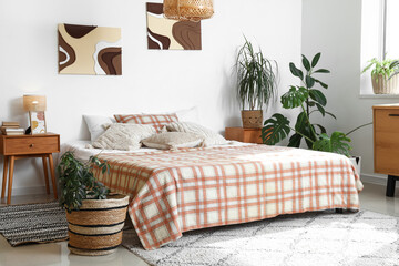 Cozy bed and houseplants in interior of bedroom