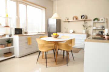 Blurred view of kitchen with dining table, counters and shelf units