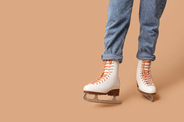 Legs of girl in ice skates on brown background